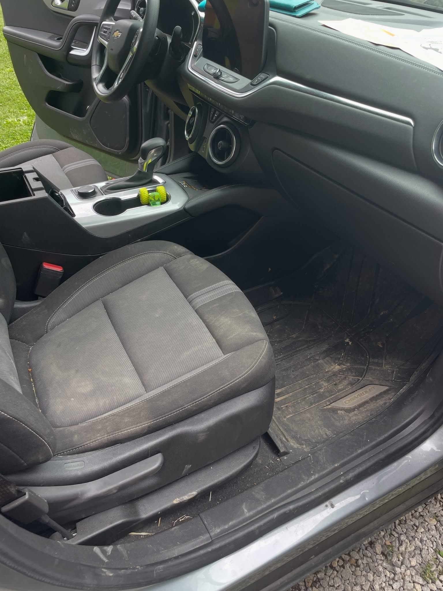 Dirty driver's seat and footwell of a Chevrolet Blazer before cleaning
