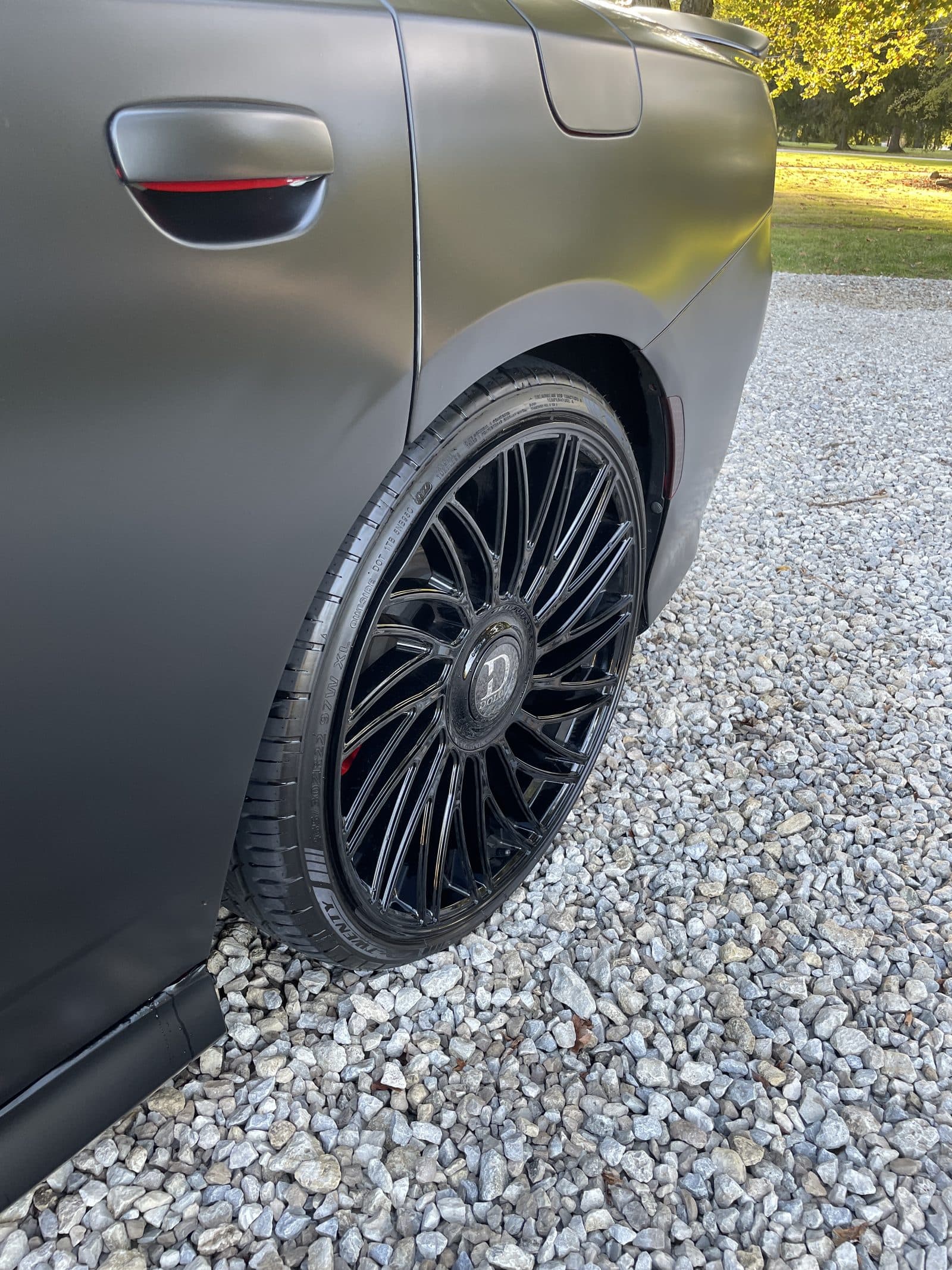 Rear quarter panel and black alloy wheel of a matte-wrapped car