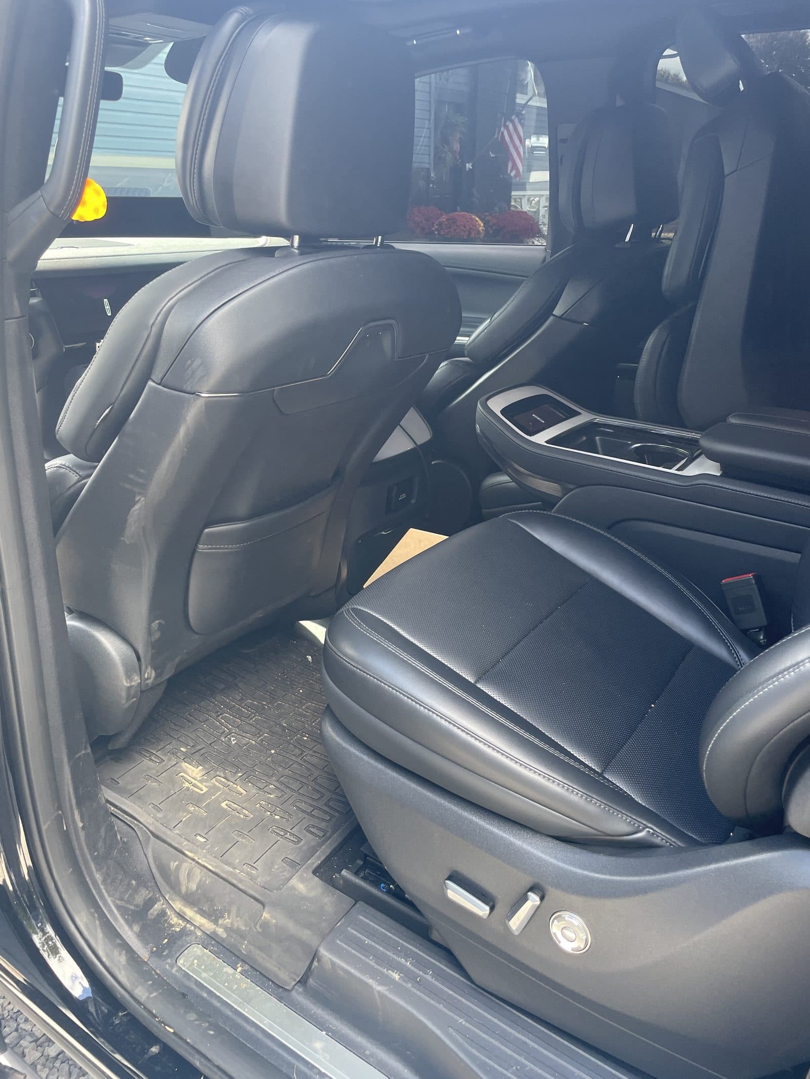 Dirty second-row floor mat and door sill of a Lincoln Navigator before cleaning