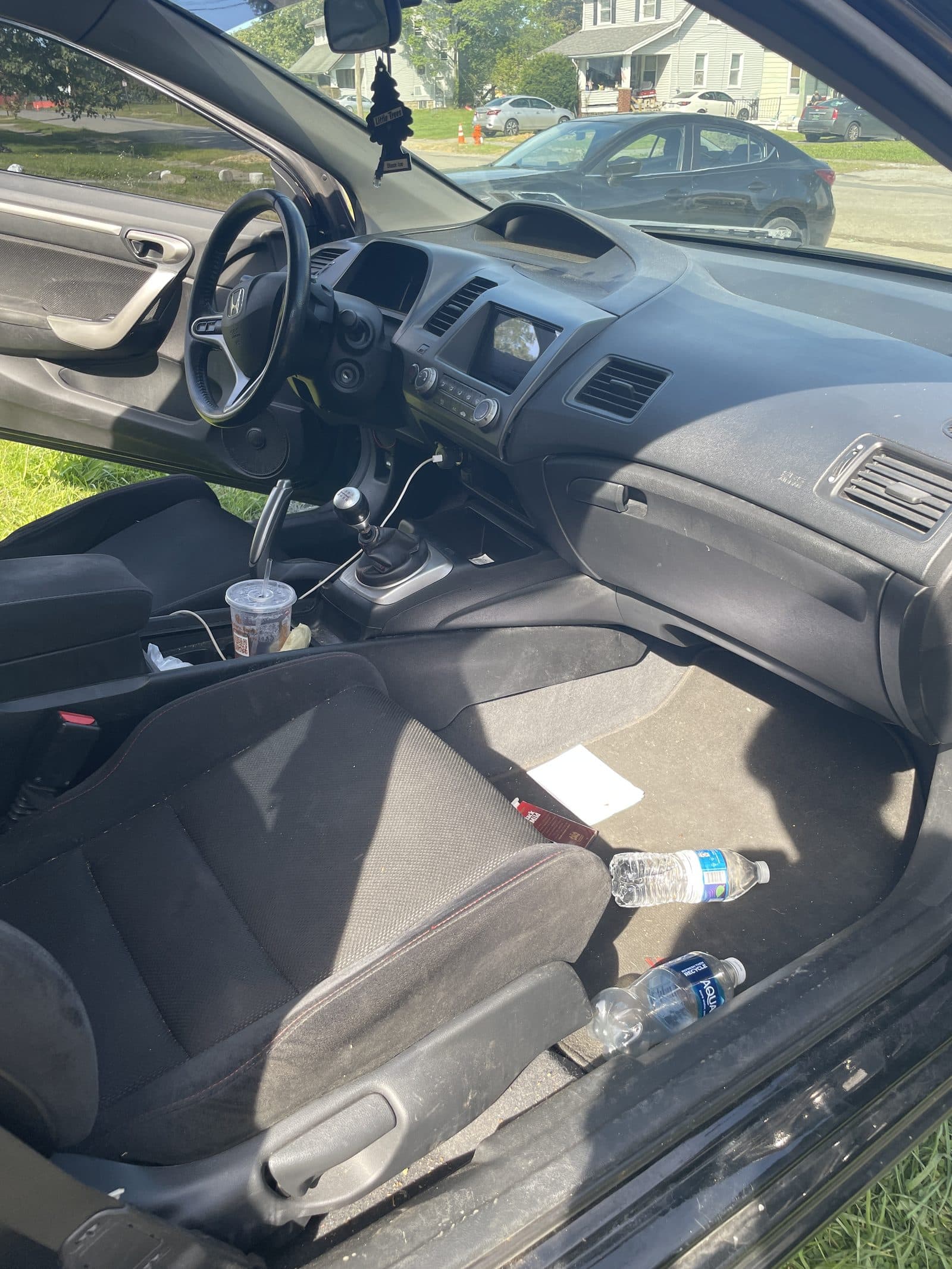 Honda Civic interior with water bottles and trash on the floor before cleaning
